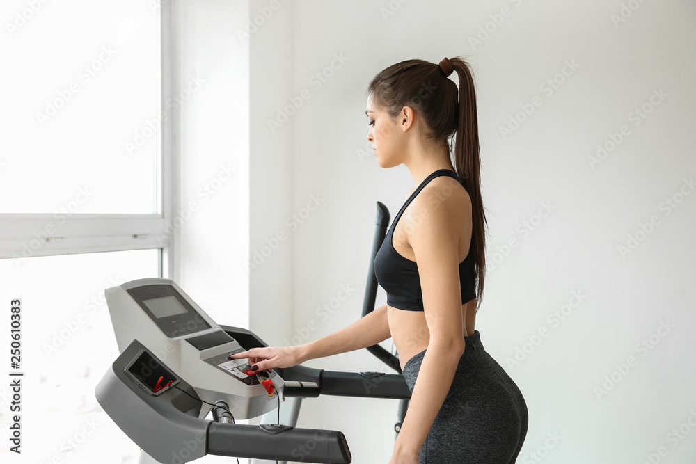 Sporty young woman on treadmill in gym