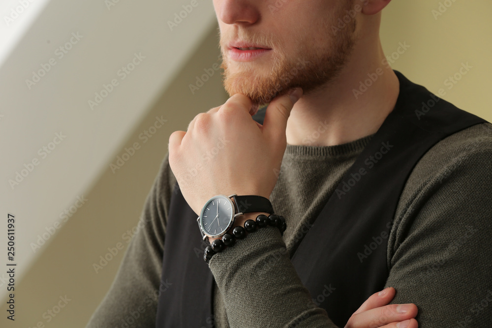 Fashionable young man with watch indoors, closeup