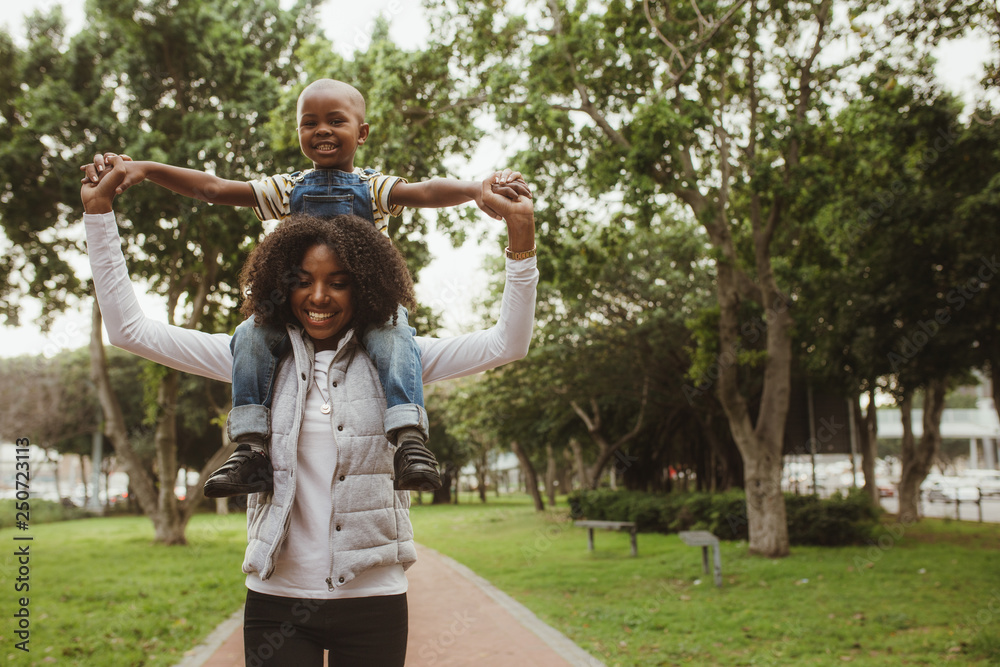 Mother carrying boy on shoulders at park