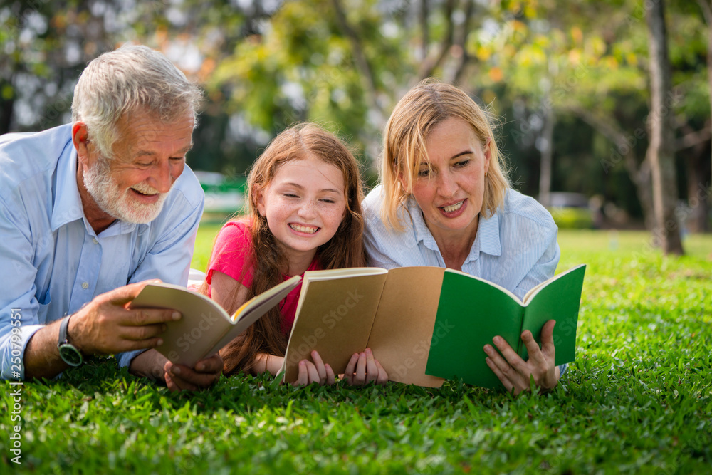 Happy family read books together in park garden.