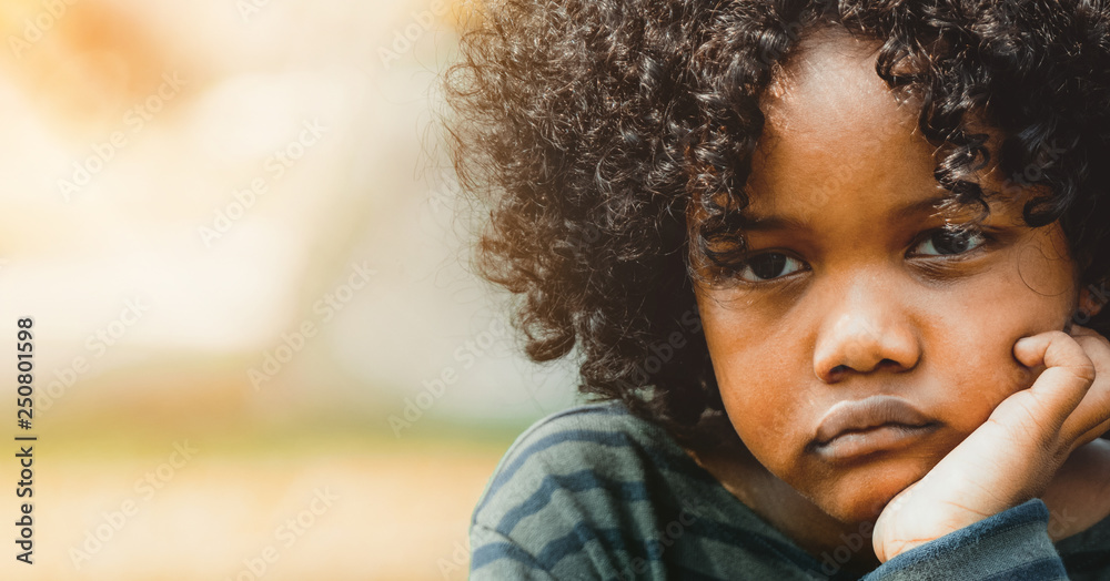 Unhappy little african american kid in the park.