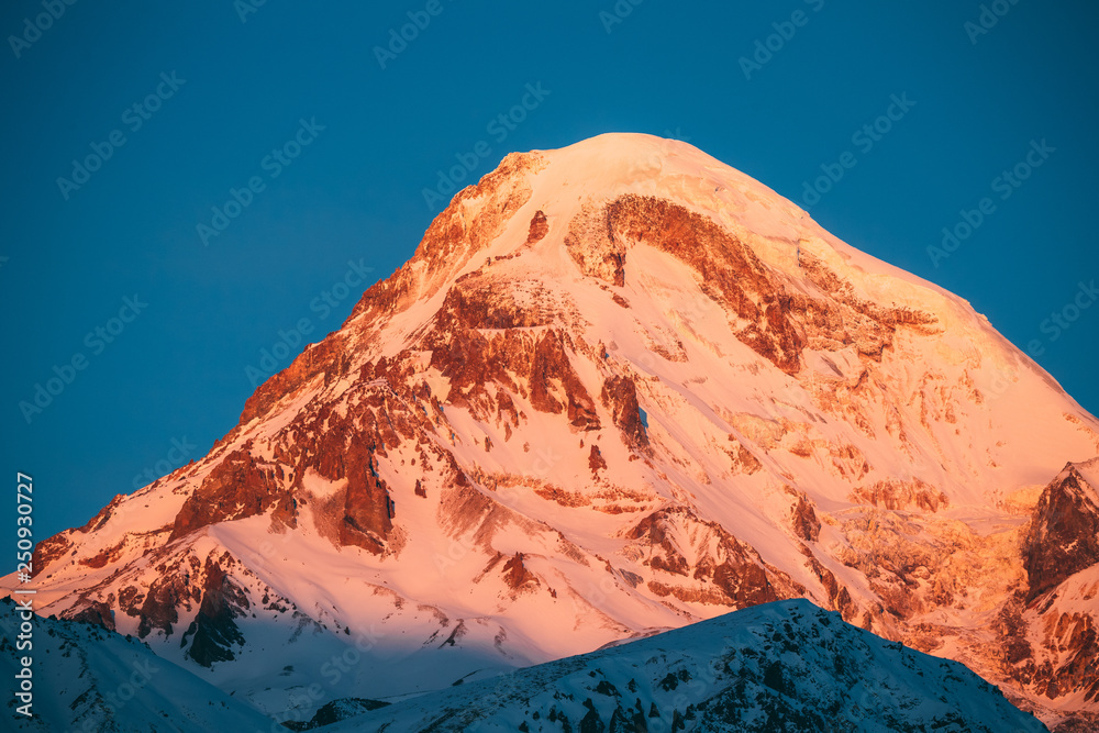 乔治亚州。卡兹贝克山在冬季日出时被雪覆盖。清晨的黎明为平克托的山顶上色