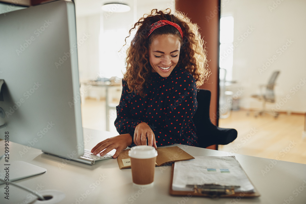 Smiling young businesswoman working at her desk in an office