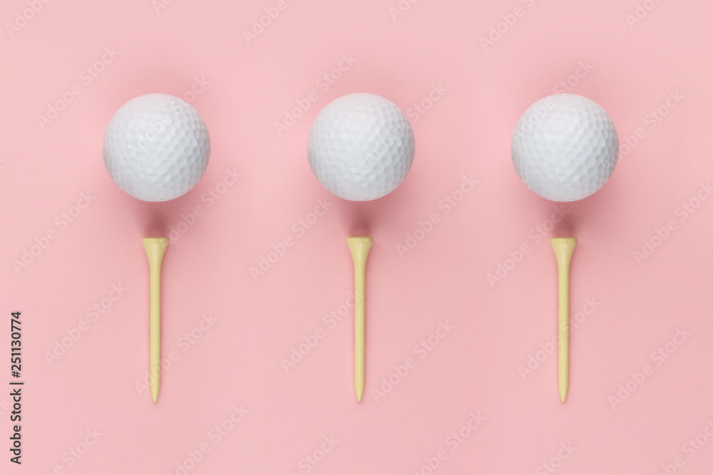 Three golf ball and wooden tee on pink background closeup