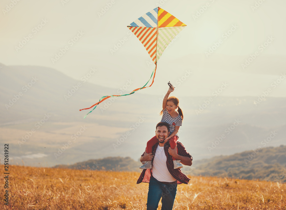 happy family father and child daughter launch  kite on meadow.