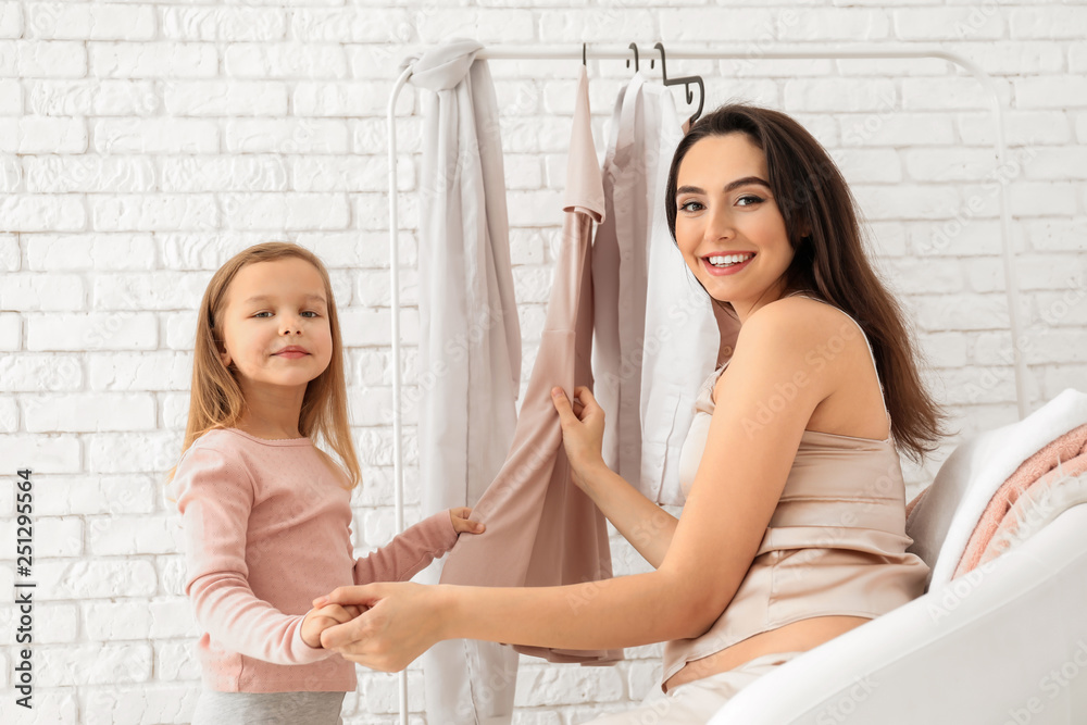 Cute little girl and her mother with stylish clothes at home