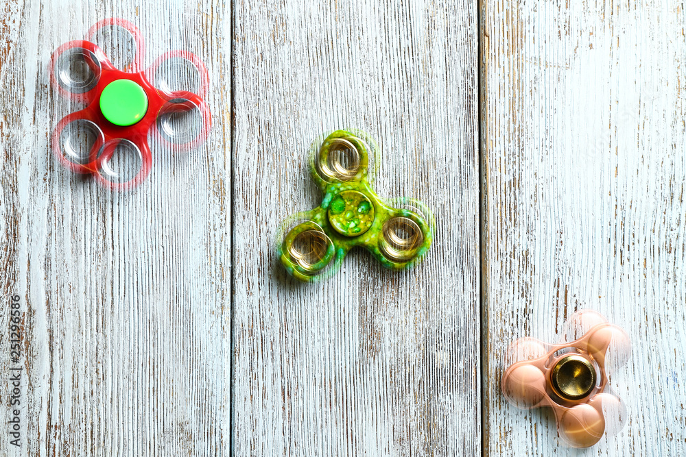 Stroboscopic photo of moving spinners on wooden background