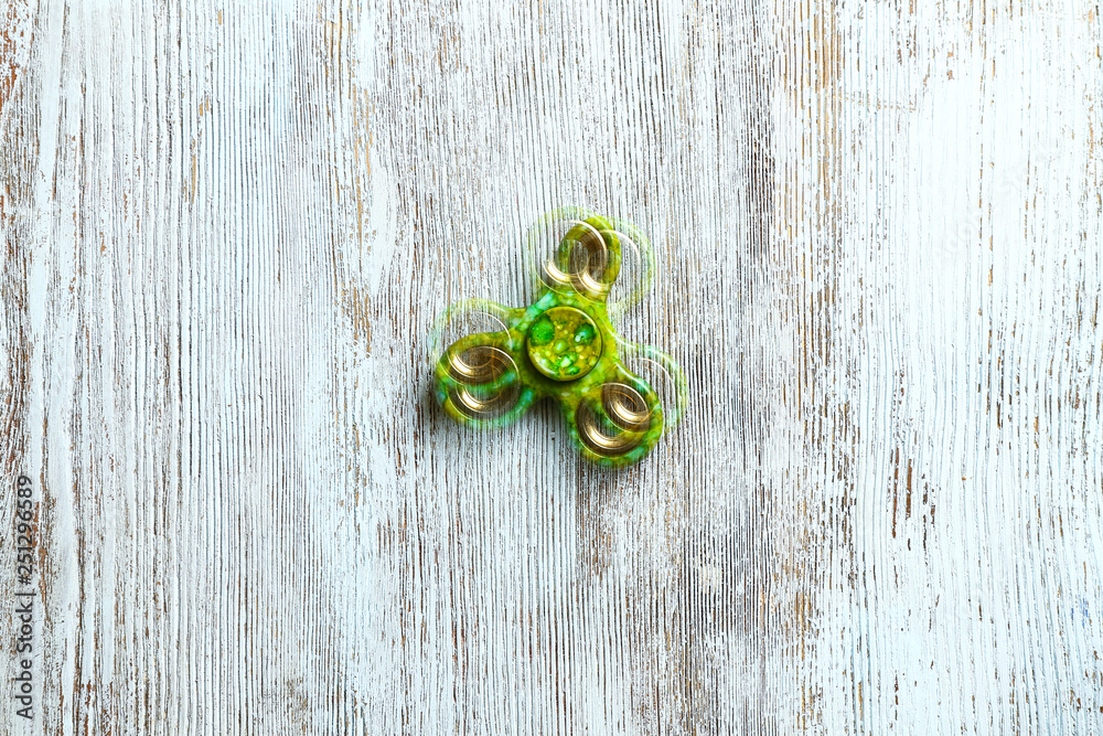 Stroboscopic photo of moving spinner on wooden background