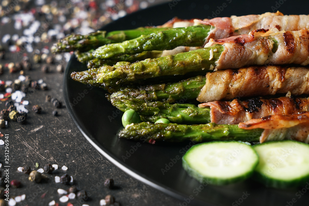 Plate with bacon wrapped asparagus on grey table, closeup