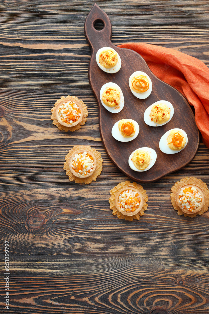 Tasty deviled eggs with tartlets on wooden table