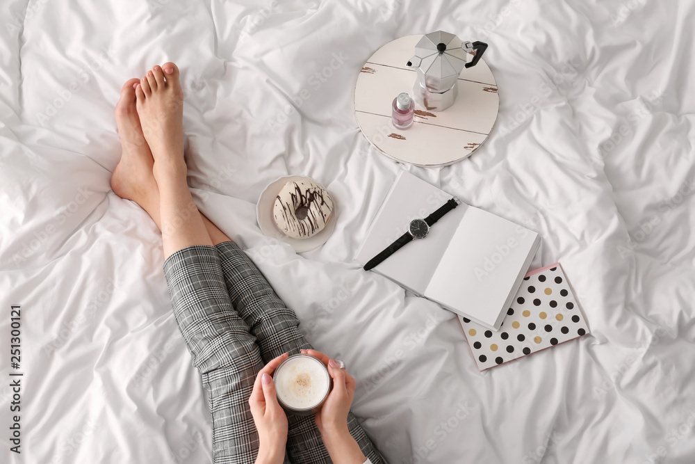 Young woman drinking coffee on bed in morning