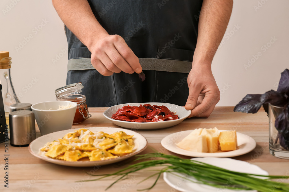 Male chef preparing for serving tasty ravioli on table