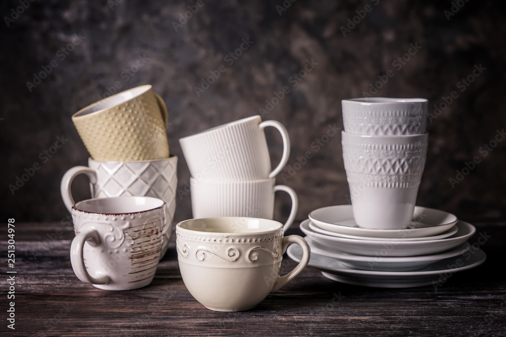 Different tea cups with saucers on wooden table