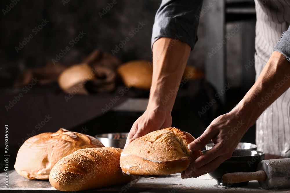 Young man with freshly baked bread in kitchen