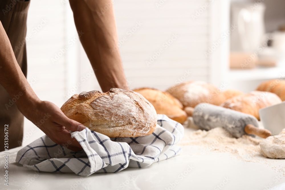 Young man with freshly baked bread in kitchen