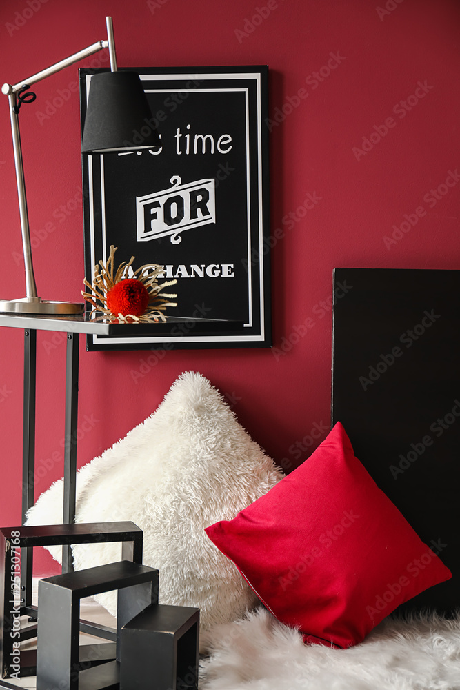 Modern table with lamp and soft pillows in interior of room