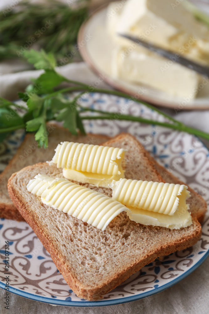 Plate with tasty butter and bread on table, closeup