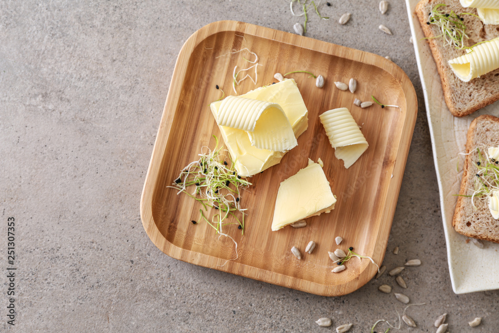 Plates with tasty butter and bread on grey table