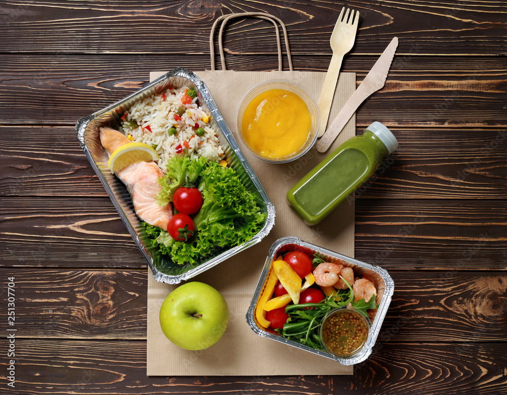 Containers with delicious food for delivery on wooden table