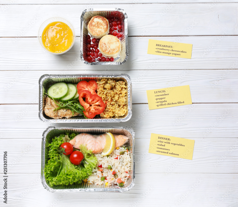 Containers with delicious food for delivery on white wooden table