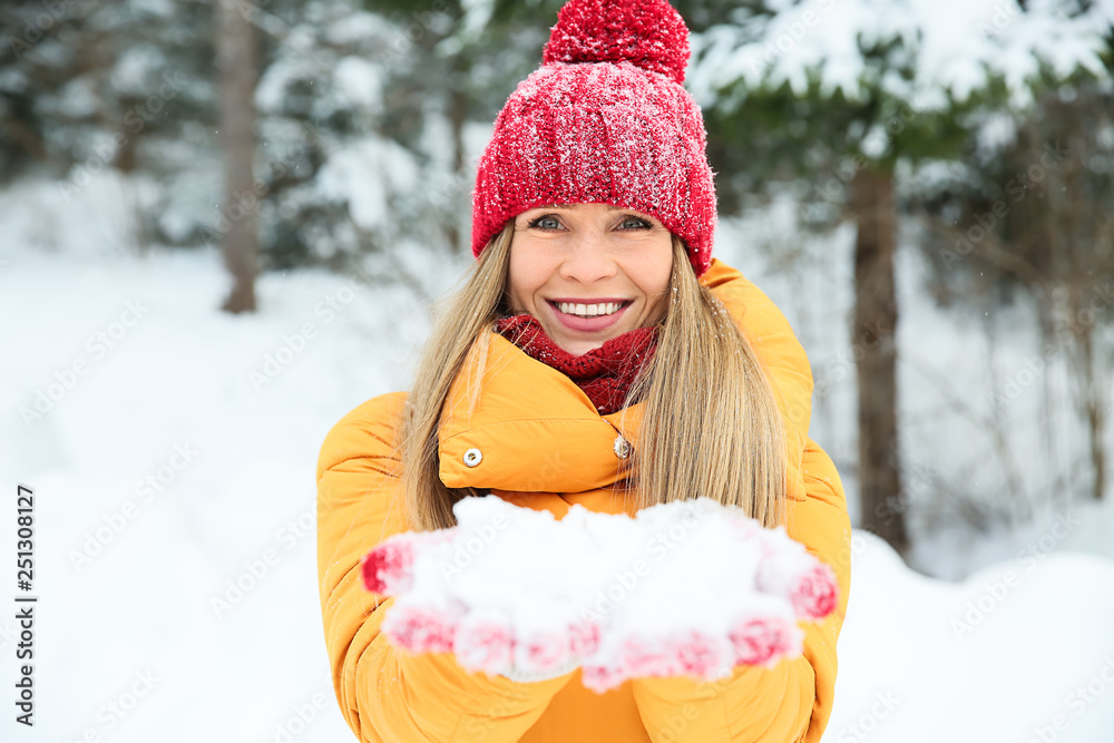 Beautiful woman with handful of snow in winter forest