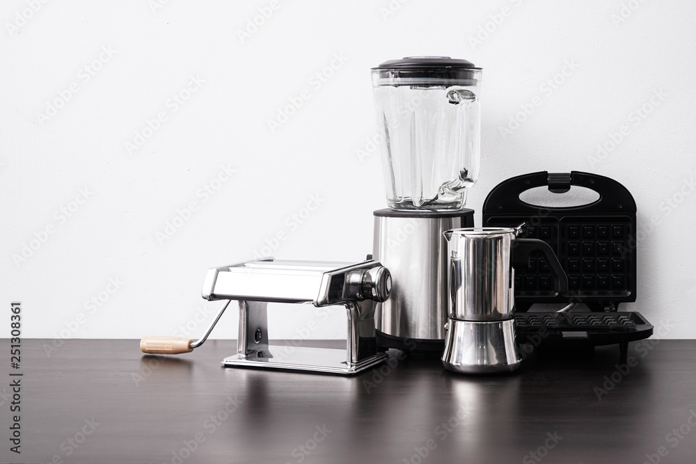 Set of kitchen appliances on table near white wall