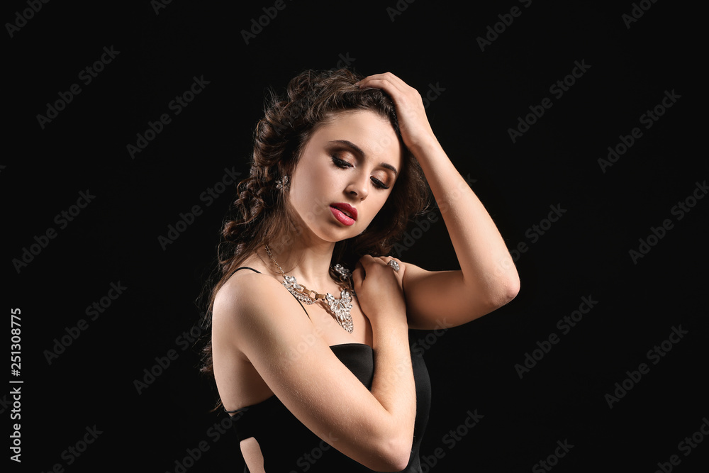 Young woman with beautiful jewelry on dark background