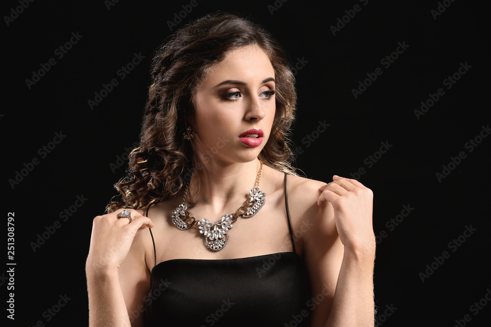 Young woman with beautiful jewelry on dark background