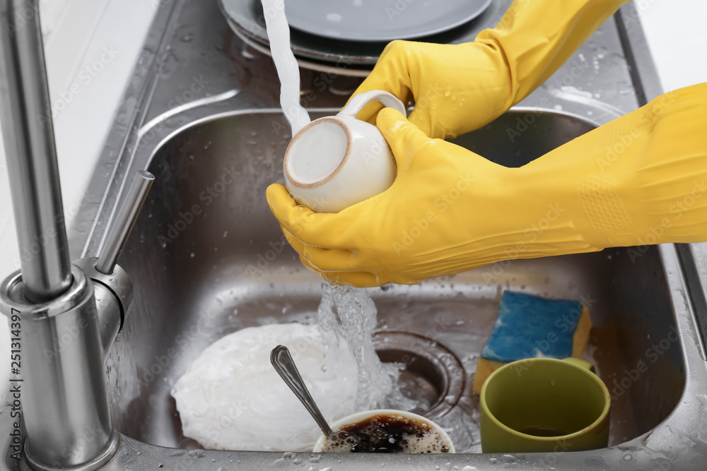 Woman washing cup in kitchen sink