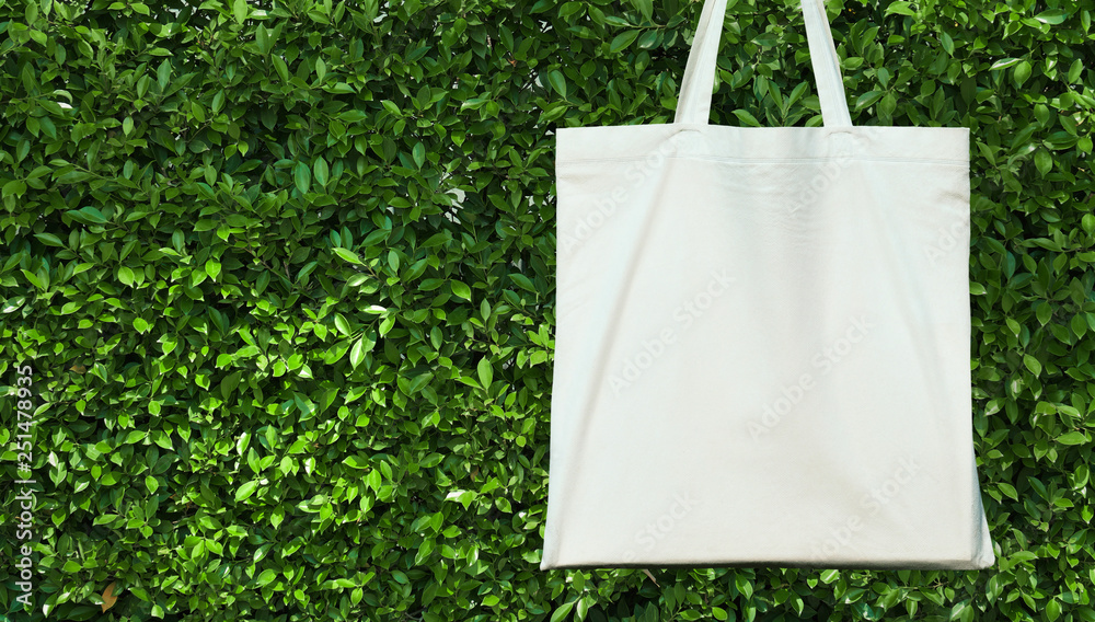 blank white cotton bag on green leavs background. eco friendly concept