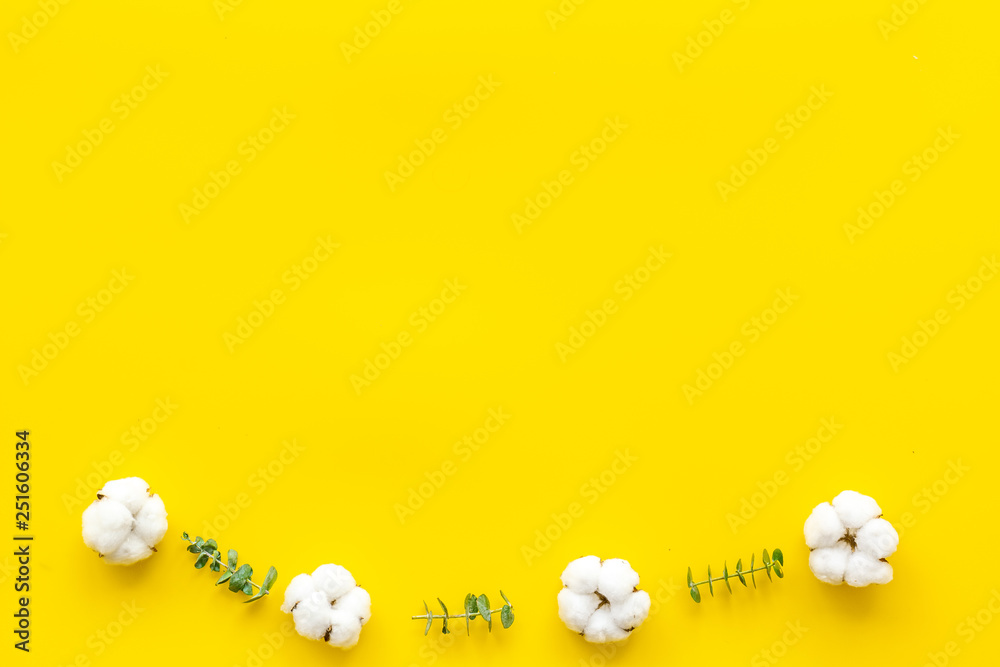 Flowers composition on yellow desk with fresh eucalyptus branches and cotton. Flat lay, top view, co