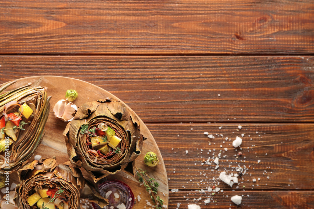 Board with tasty artichokes and vegetables on wooden table