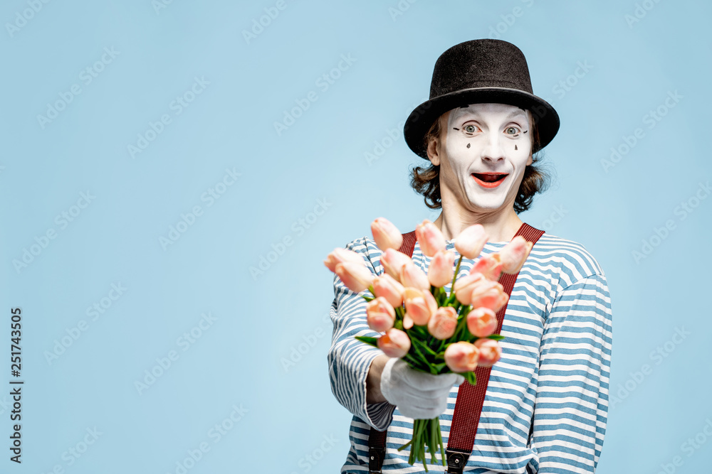 Emotional pantomime posing with tulip bouquet on the blue background indoors. Valentines Day and lo