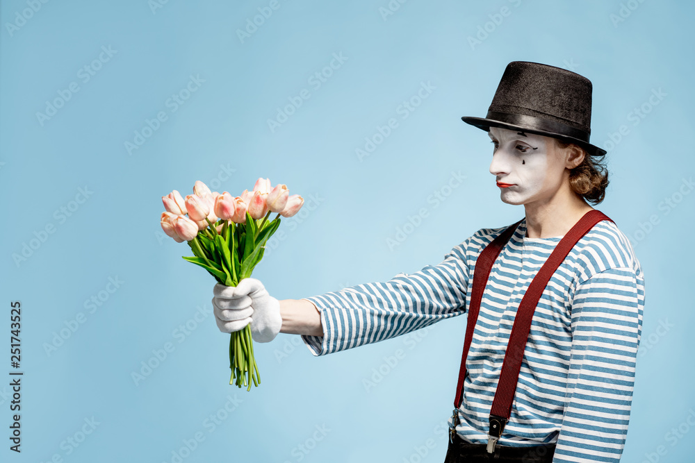 Emotional pantomime posing with tulip bouquet on the blue background indoors. Valentines Day and lo