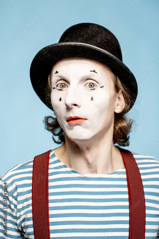 Close-up portrait of an actor as a pantomime with white facial makeup showing expressive emotions on