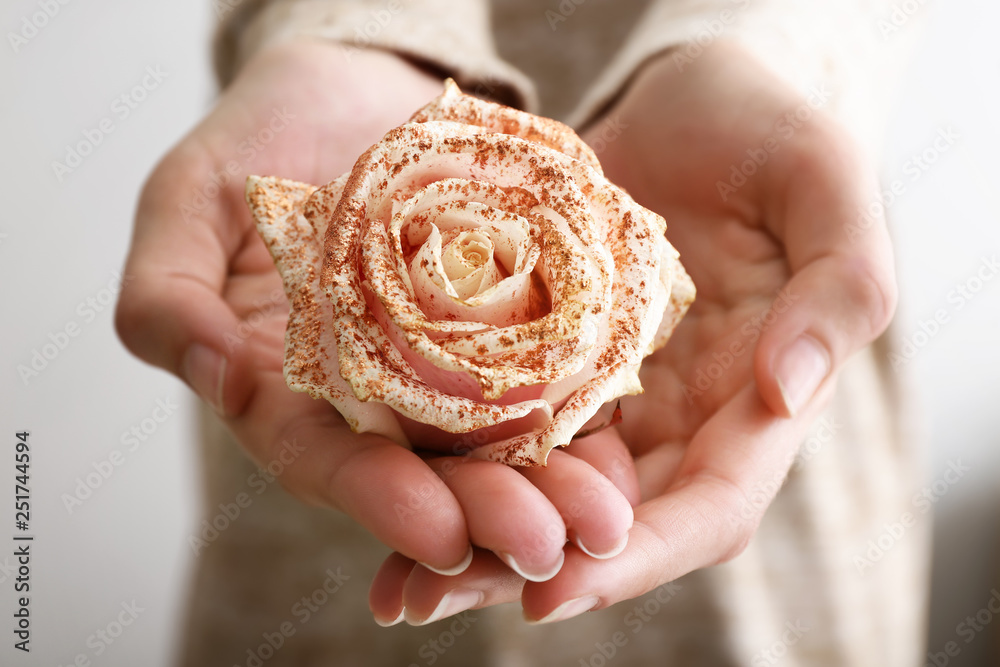 Woman holding rose with golden glitters, closeup