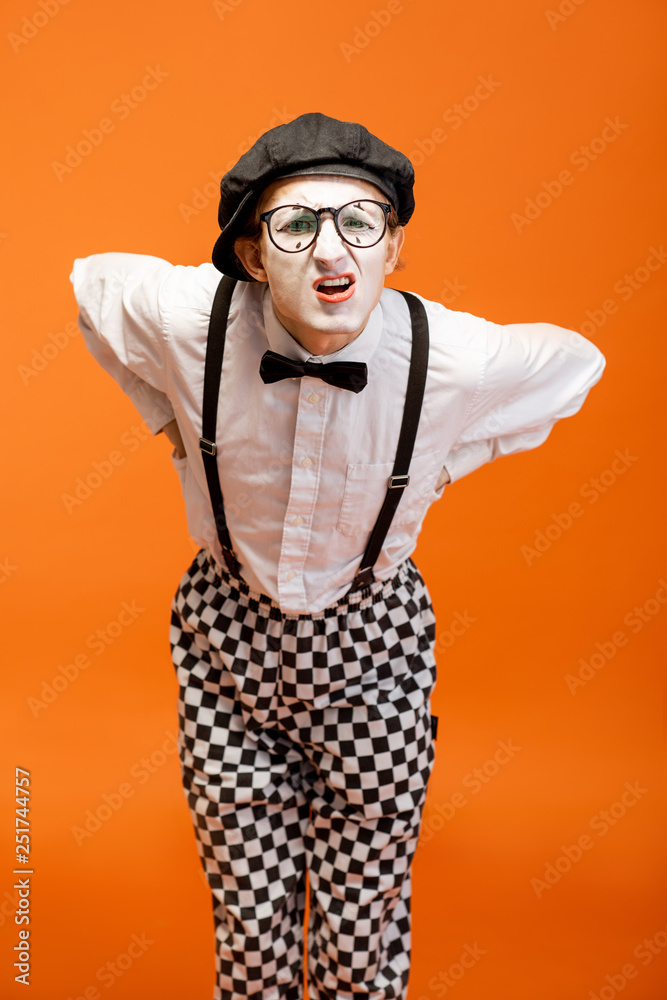 Portrait of an actor as a pantomime with white facial makeup showing expressive emotions on the oran