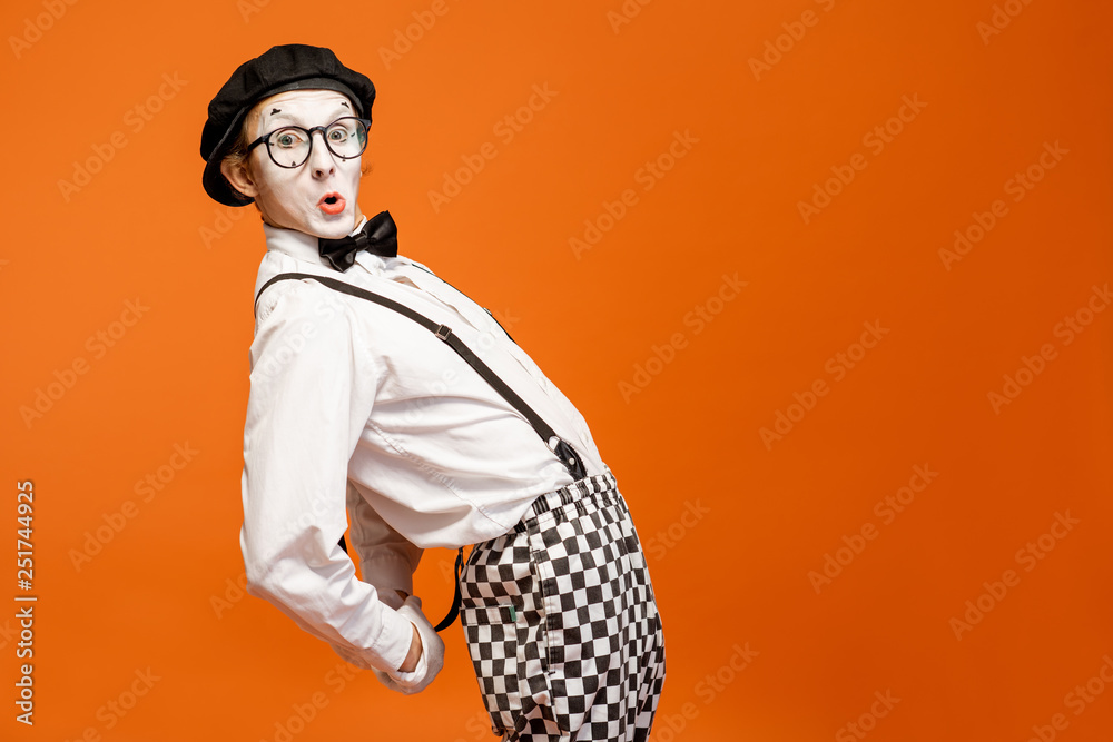 Portrait of an actor as a pantomime with white facial makeup showing expressive emotions on the oran