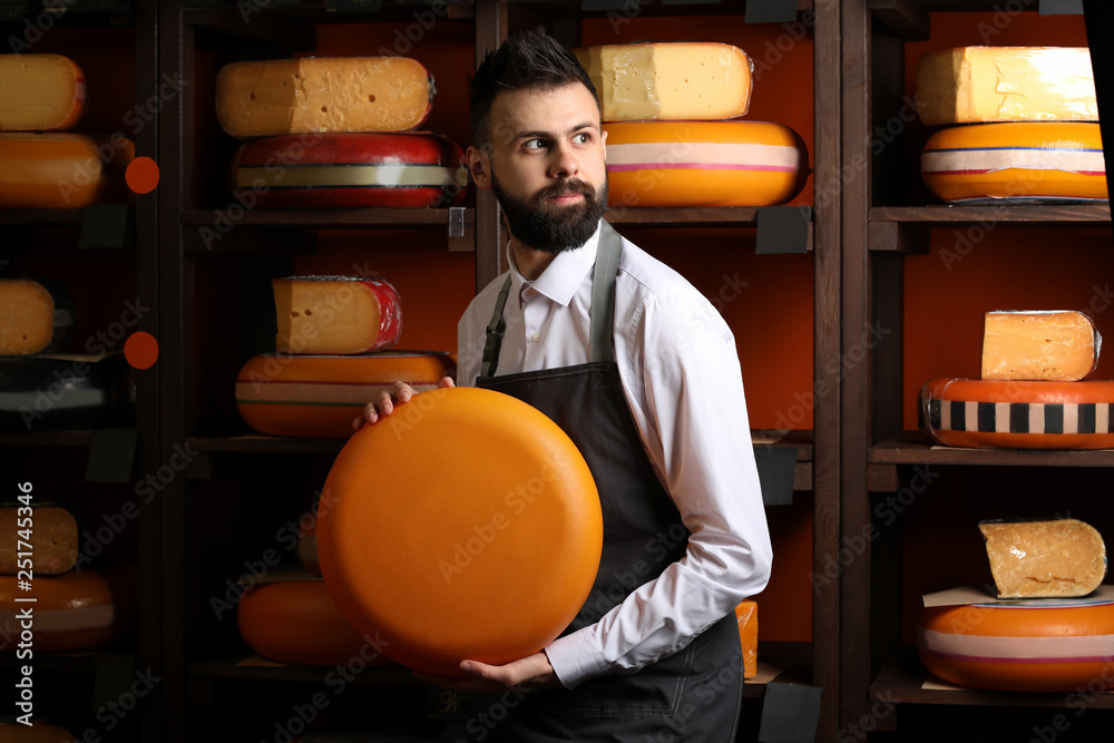 Male seller with delicious cheese in store