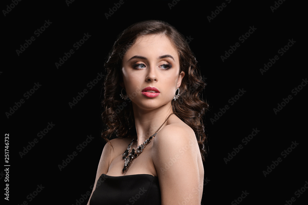 Young woman with beautiful jewelry on dark background