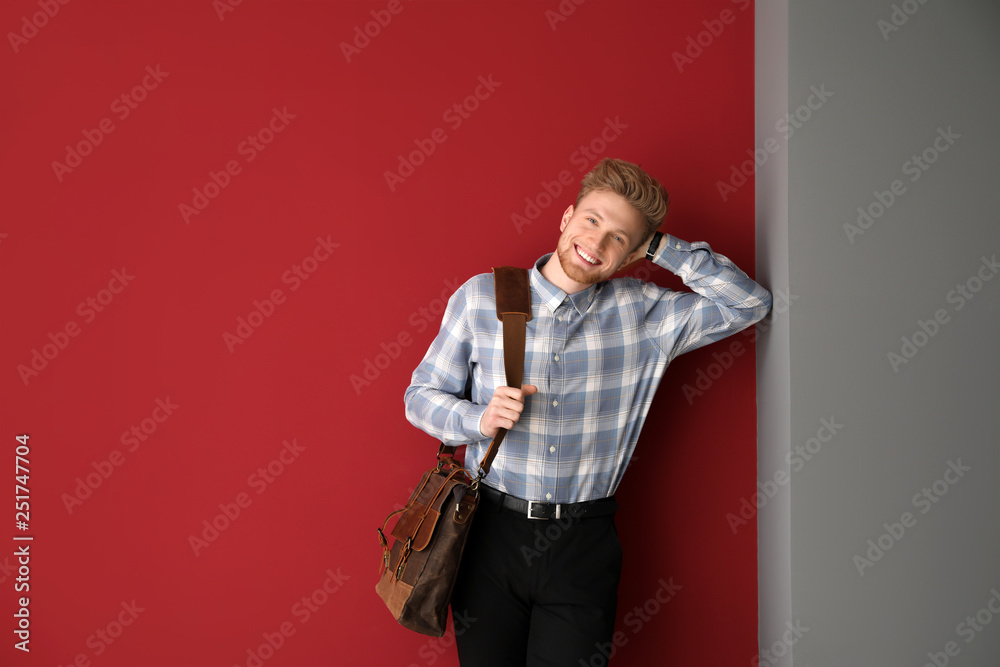 Handsome man with stylish briefcase near color wall