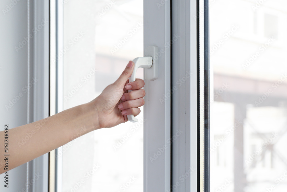 Young woman opening window in flat