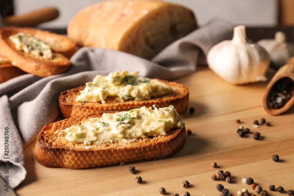 Sliced bread with garlic spreading on wooden table