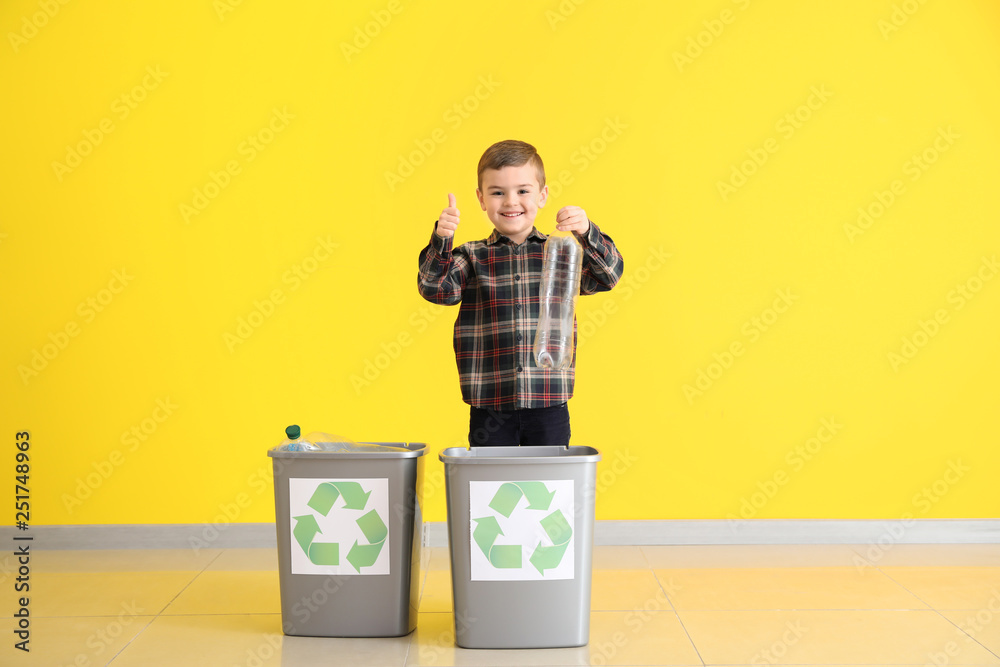 Little boy throwing garbage into trash bins near color wall. Concept of recycling