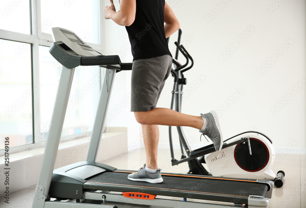 Sporty young man on treadmill in gym