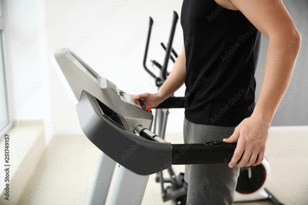 Sporty young man on treadmill in gym