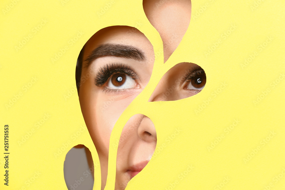 Young woman with beautiful eyebrows visible through cut color paper