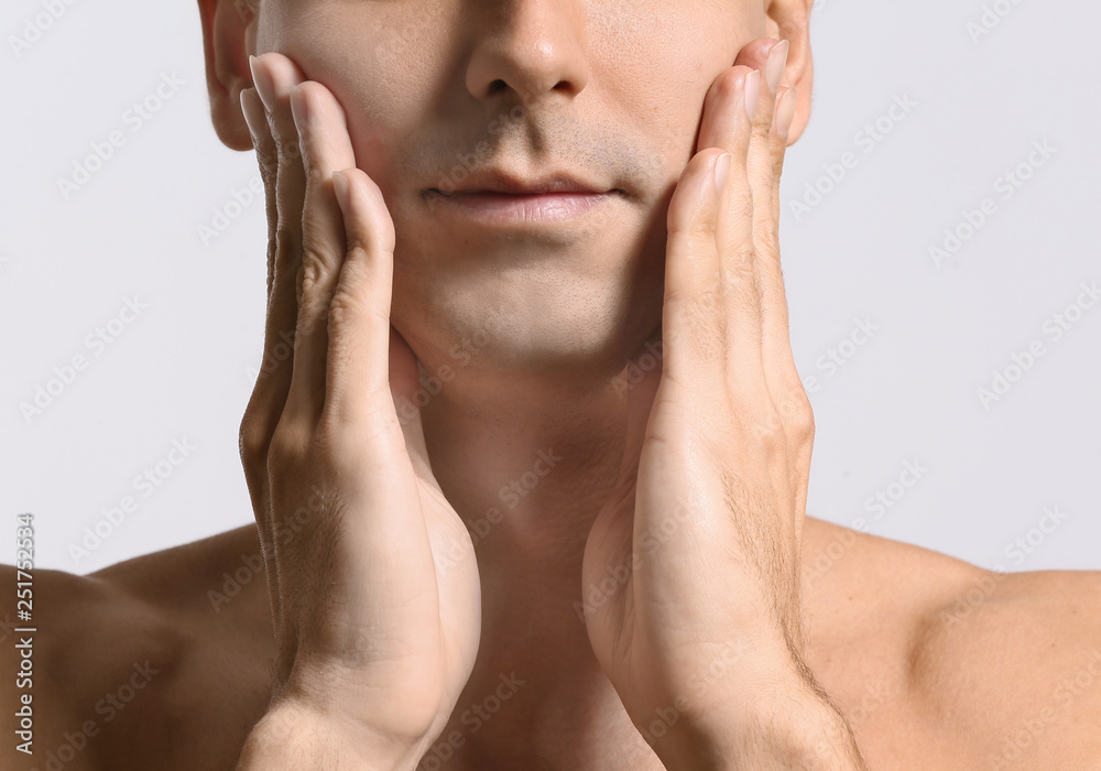 Man giving himself face massage on light background