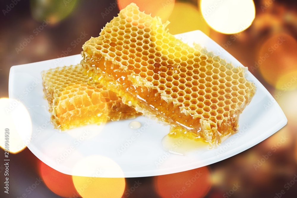 Honey with spoon in glass bowl on glossy background