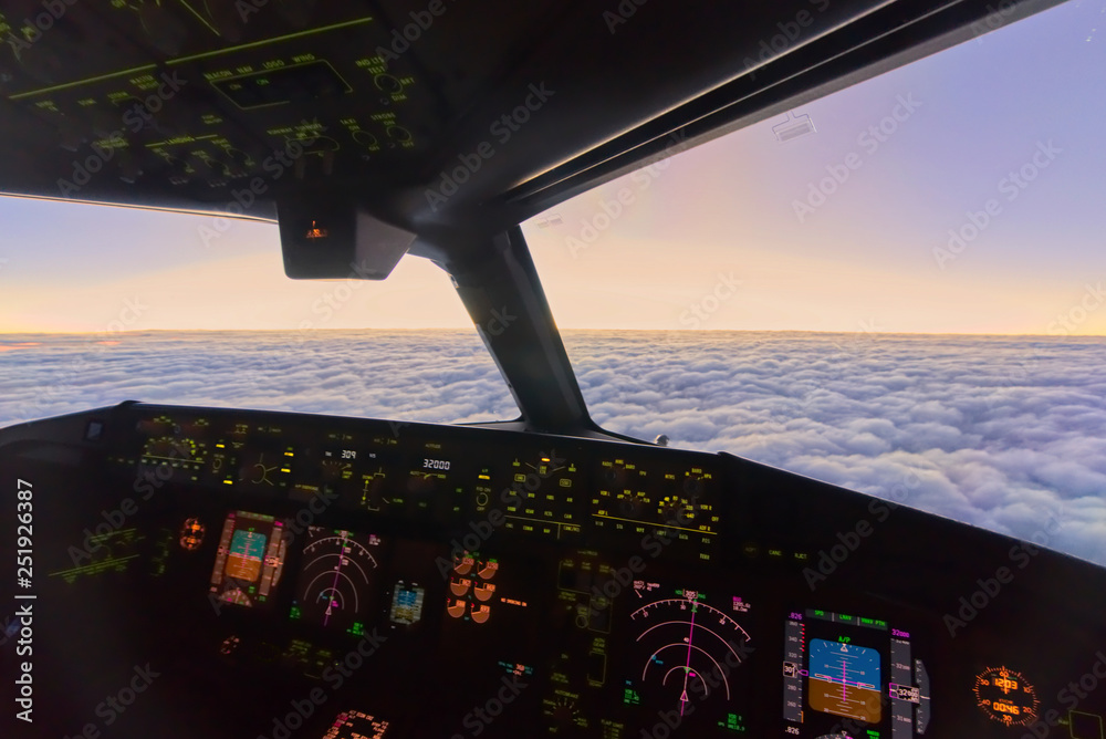 View from inside cockpit at copilot seat when airplane flying at high altitude over the clouds in th